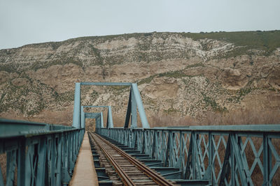 Footbridge over mountain against clear sky