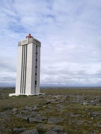 Lighthouse by sea against sky