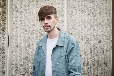 Portrait of young man standing against wall