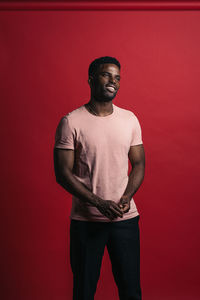 Portrait of young man standing against red background