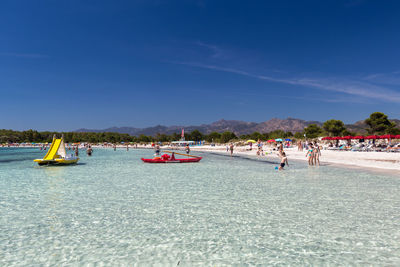 People on beach against blue sky