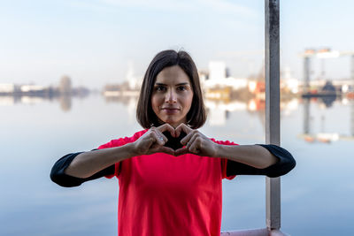 Cute young woman showing heart sign with hands on a boat