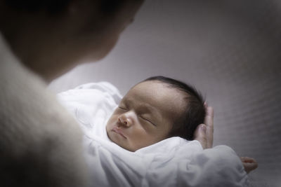 Close-up of mother holding newborn son on bed