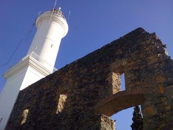 Low angle view of ruined wall and lighthouse