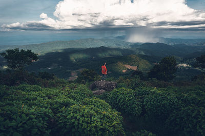 High angle view of man standing on mountains against cloudy sky