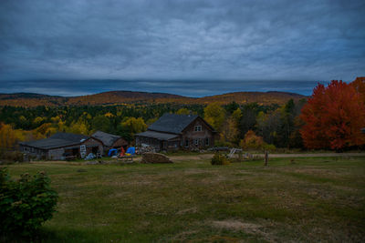 Houses on countryside landscape against cloudy sky