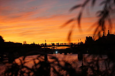 Silhouette bridge over river against romantic sky at sunset