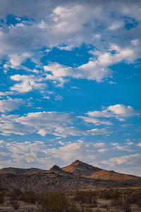 Desert peaks in early morning light with blue sky and clouds above