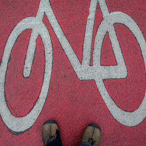Low section of man standing by bicycle lane sign on footpath
