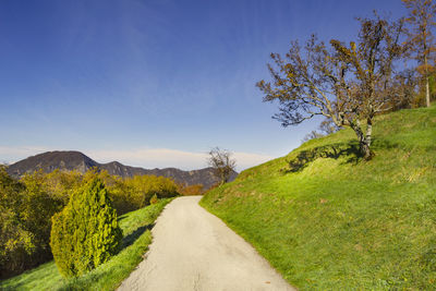 Empty road along landscape and against blue sky