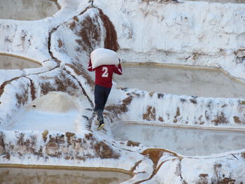 Rear view of man walking on snow