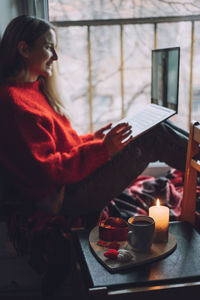 Midsection of woman using phone while sitting on table