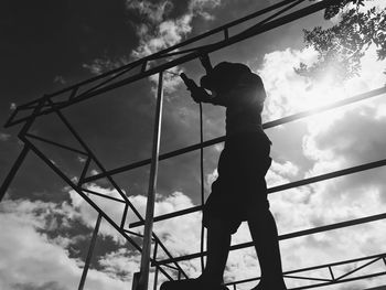 Low angle view of silhouette boy playing against sky