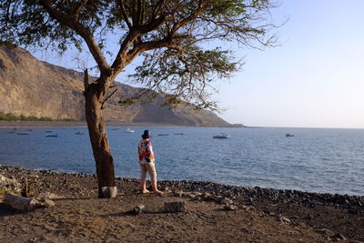 Full length of young woman standing by lake against sky