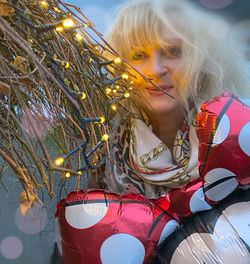 Smiling woman standing by illuminated christmas lights