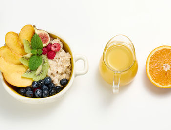 A plate with oatmeal and fruit, half a ripe orange and freshly squeezed juice in a 