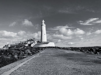 Lighthouse amidst buildings against sky