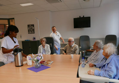 Caretakers and senior people at table in nursing home