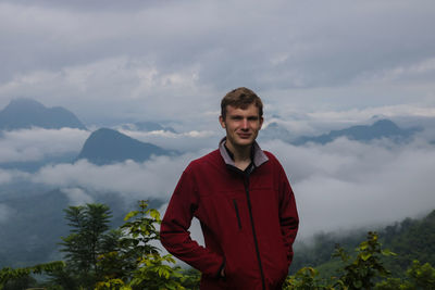 Portrait of young man standing against mountain