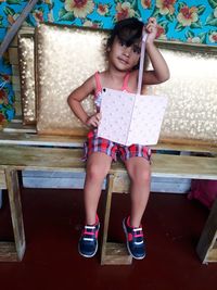 Portrait of cute girl holding book while sitting at home