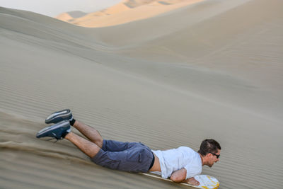 Full length of man sandboarding in desert
