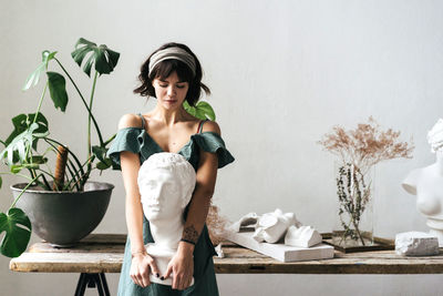 Female artist holding bust at art studio