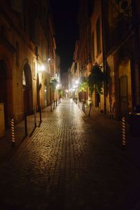 Illuminated street amidst buildings in town at night