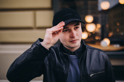 Young man looking away while standing against building