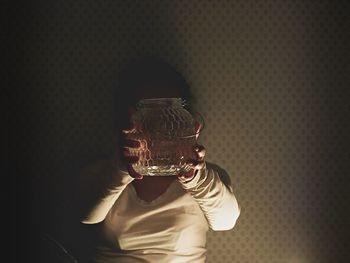 Close-up of young woman using mobile phone against black background