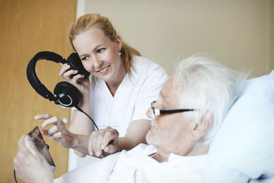 Smiling female nurse listening music through headphones while using digital tablet in hospital ward