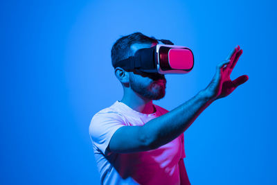 Side view of young man photographing against blue background