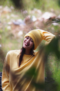 Smiling young woman wearing knit hat seen through plants at public park