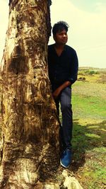 Full length of young man standing on tree trunk