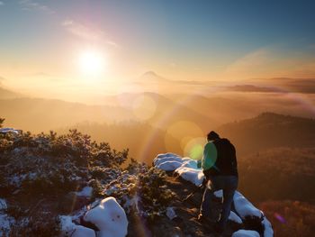 Professional photographer takes picture of  autumnal daybreak, rocks covered with fresh powder snow