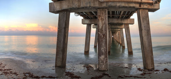 Pier on sea against sky at sunset