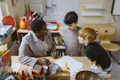 Female teacher explaining schoolboys in classroom