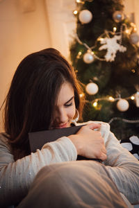 Woman relaxing on christmas tree at home