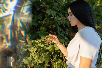 Young woman looking at berries growing on plant