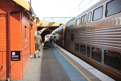 Rear view of man walking at railroad station platform