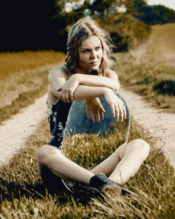 Full length of young woman sitting on field