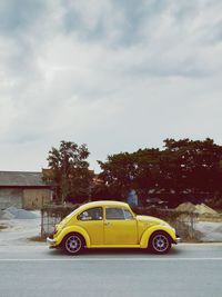 Yellow car on road against sky