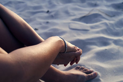 Low section of woman on sand at beach