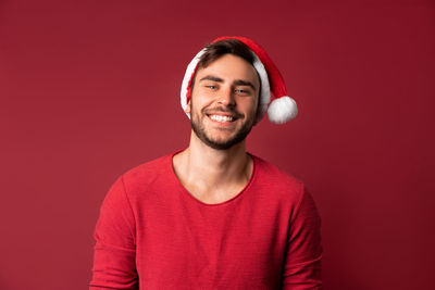 Portrait of smiling young man against red background