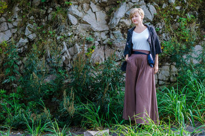 Young woman standing against rock formation in forest