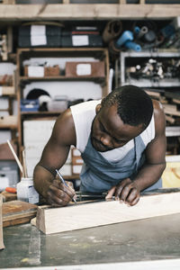 Male entrepreneur marking on wood while upcycling at workshop