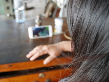 Cropped image of woman using phone on table