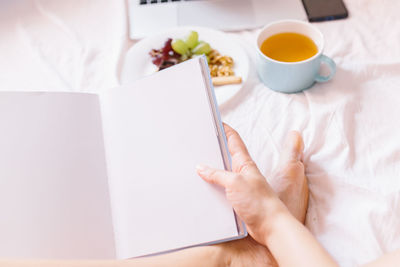 High angle view of hand holding book on table