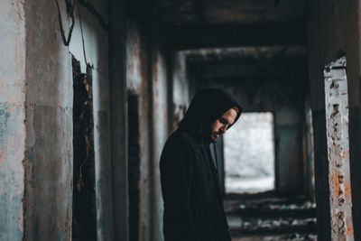 Side view of man standing in abandoned building