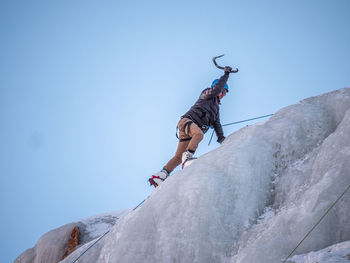 Low angle view of hiker climbing ice