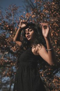 Portrait of young woman standing by tree